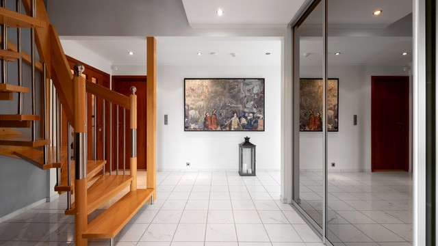 Hall med italienske marmorfliser på gulvet, innfelte spotter og skyvedørsgarderobe med speilfronter.