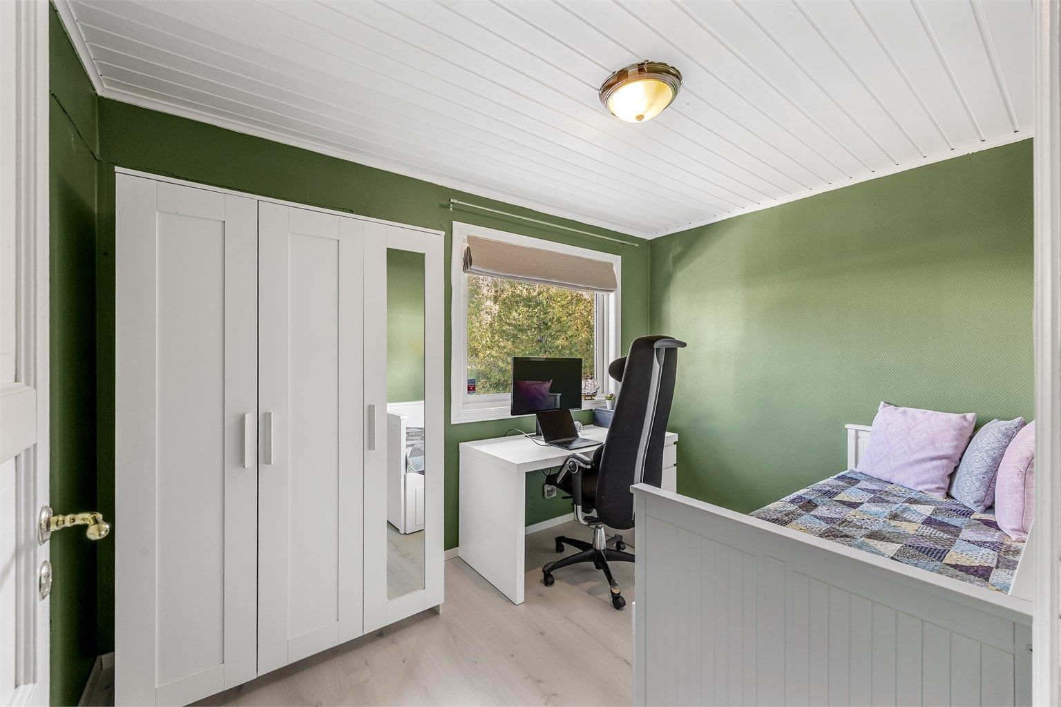 Soverom med grønnmalte panelvegger, garderobeskap og plass til kontorpult.