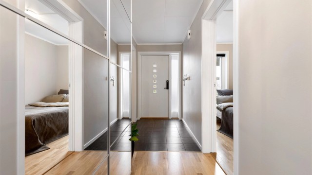 Velkommen inn. Entréen har flislagt gulv med varmekabler for komfort, og en praktisk skyvedørsgarderobe. Ytterdøren er utstyrt med elektronisk kodelås.