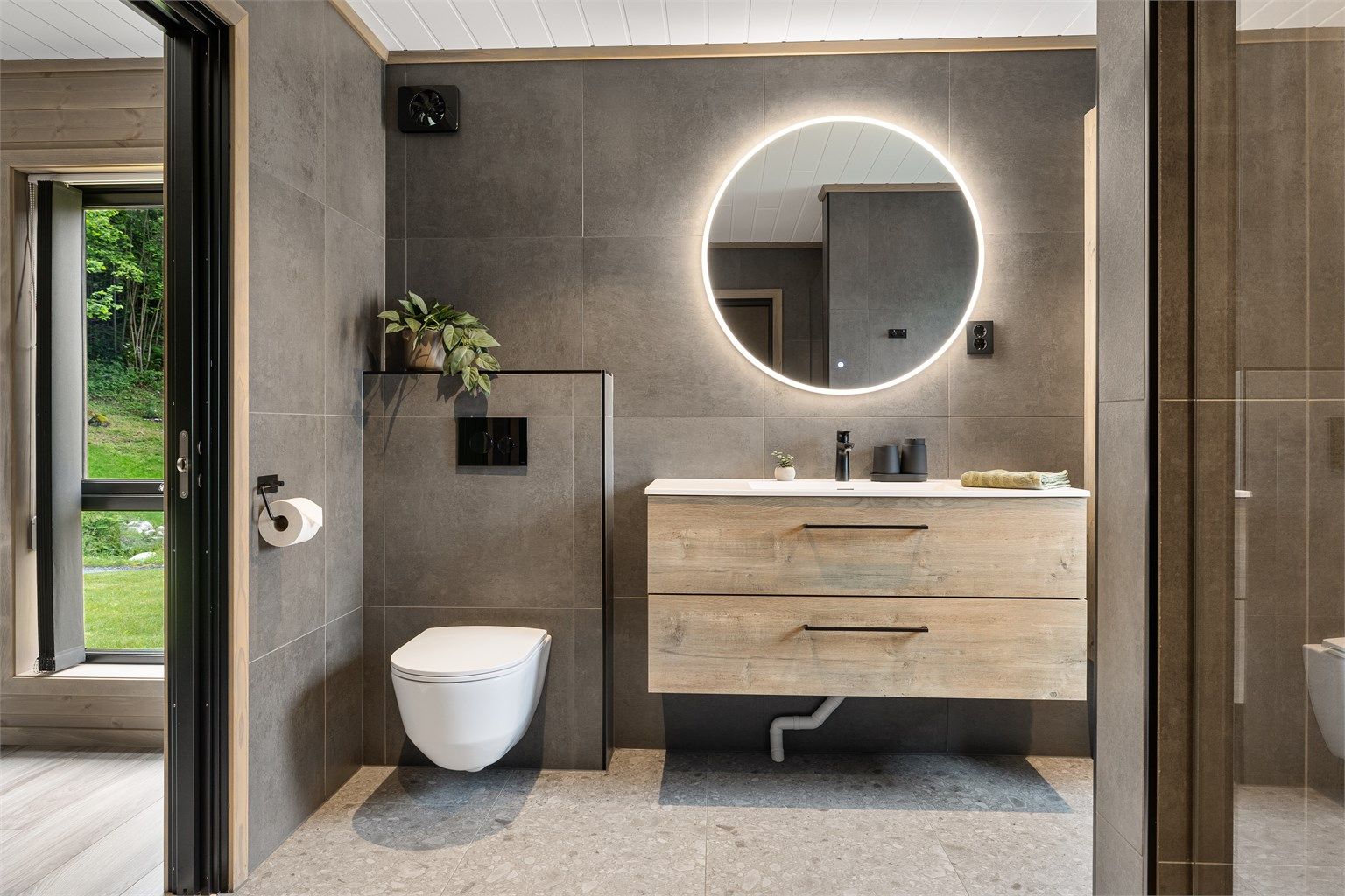 Badet har store og moderne fliser og god belysning med spotter og integrert belysning i speilet