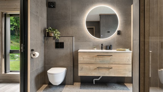Badet har store og moderne fliser og god belysning med spotter og integrert belysning i speilet