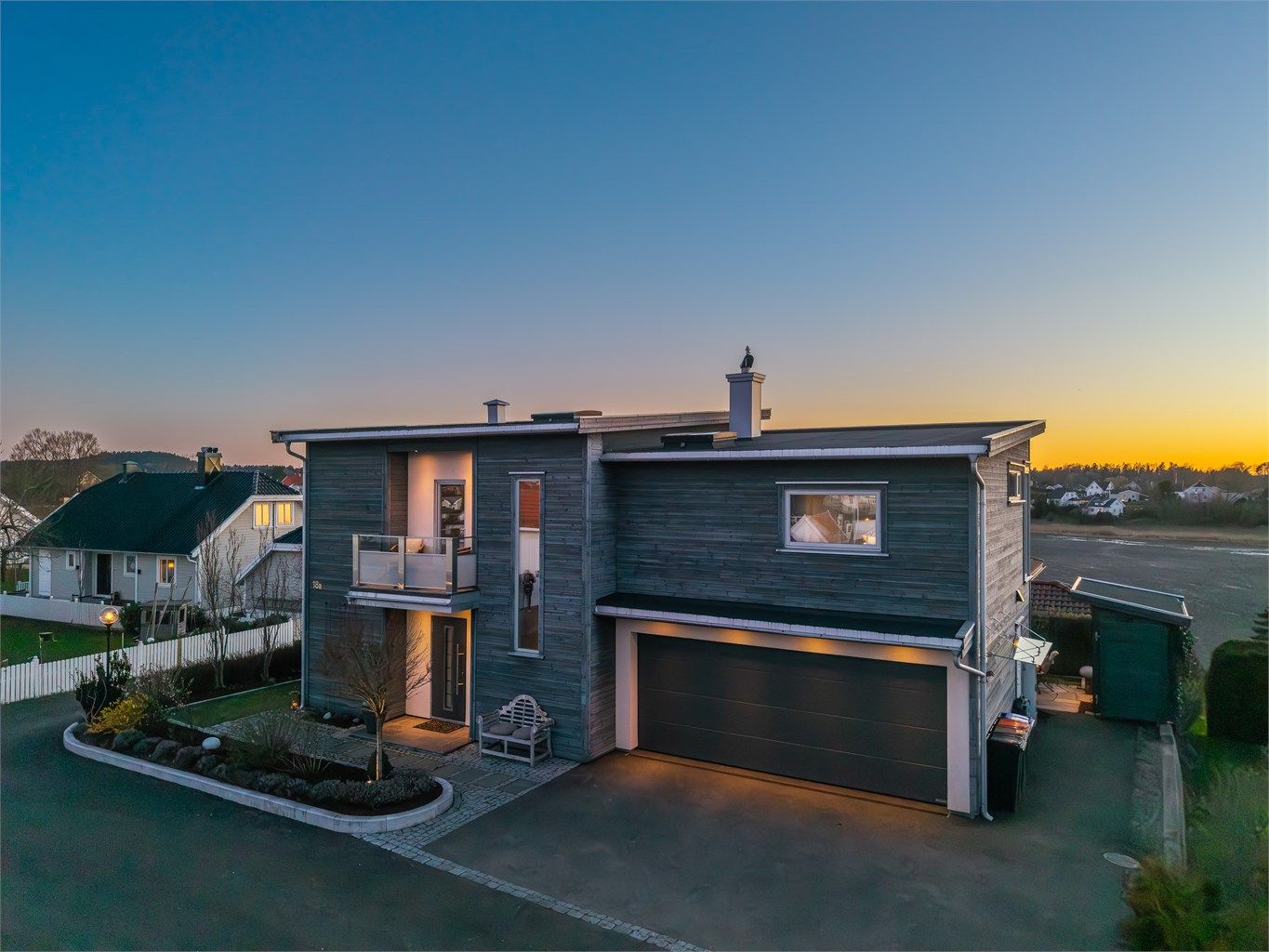 Eneboligen har en moderne arkitektur med en kombinasjon av pussede fasader og trekledning.