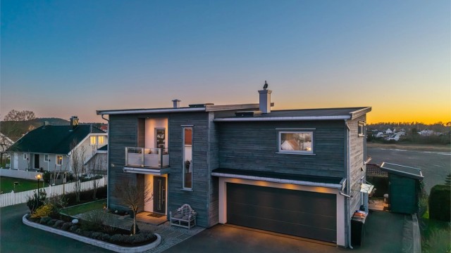 Eneboligen har en moderne arkitektur med en kombinasjon av pussede fasader og trekledning.