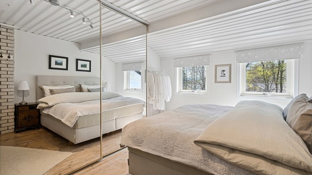 Romslig hovedsoverom med stor skyvedørsgarderobe av speil. Store vindusflater som gir godt med lysinnslipp.
