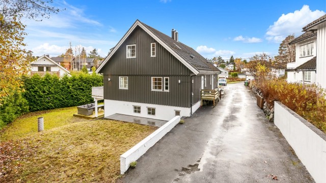 Asfaltert adkomstvei og gårdsplass samt en stor hage med hekk som gir lite innsyn.