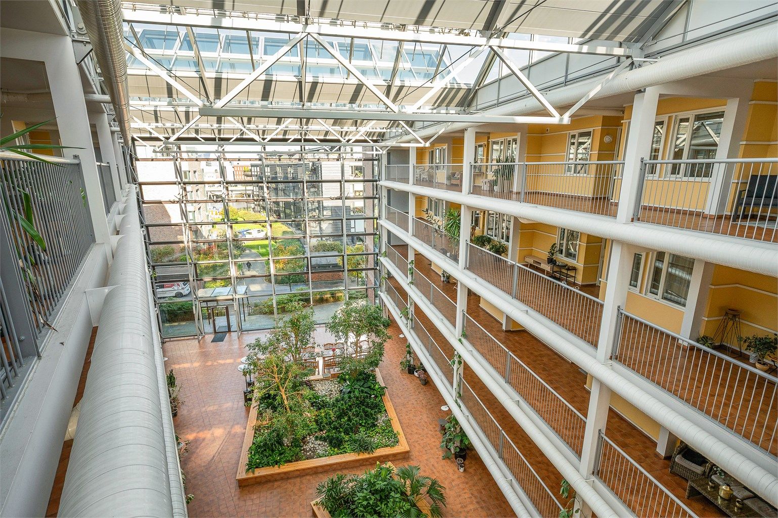 Sameiets store, overbygde glassatrium med beplantning og felles sitteområder.