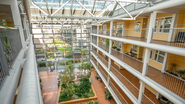 Sameiets store, overbygde glassatrium med beplantning og felles sitteområder.