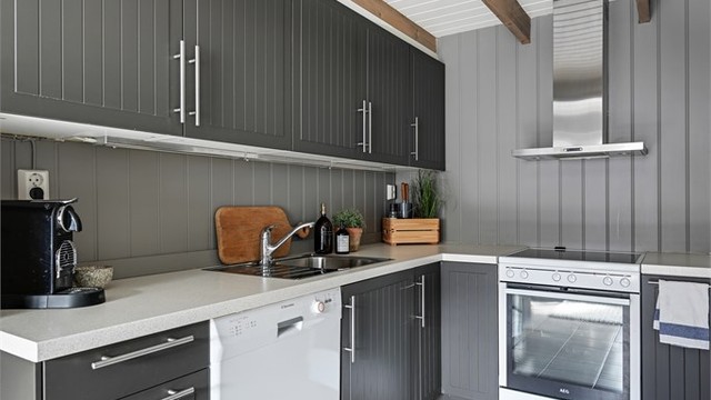 Kjøkkeninnredningen har moderne, mørke fronter og laminat benkeplate.