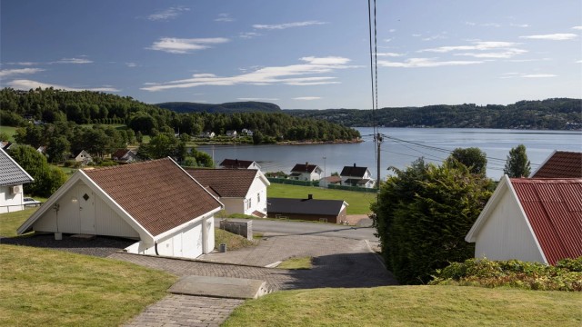 Skrånende tomt som er lettstelt og pent opparbeidet med gressplen, hekk, trær og diverse beplantninger.