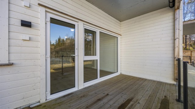 Flott terrasse med takoverbygg og glassrekkverk.