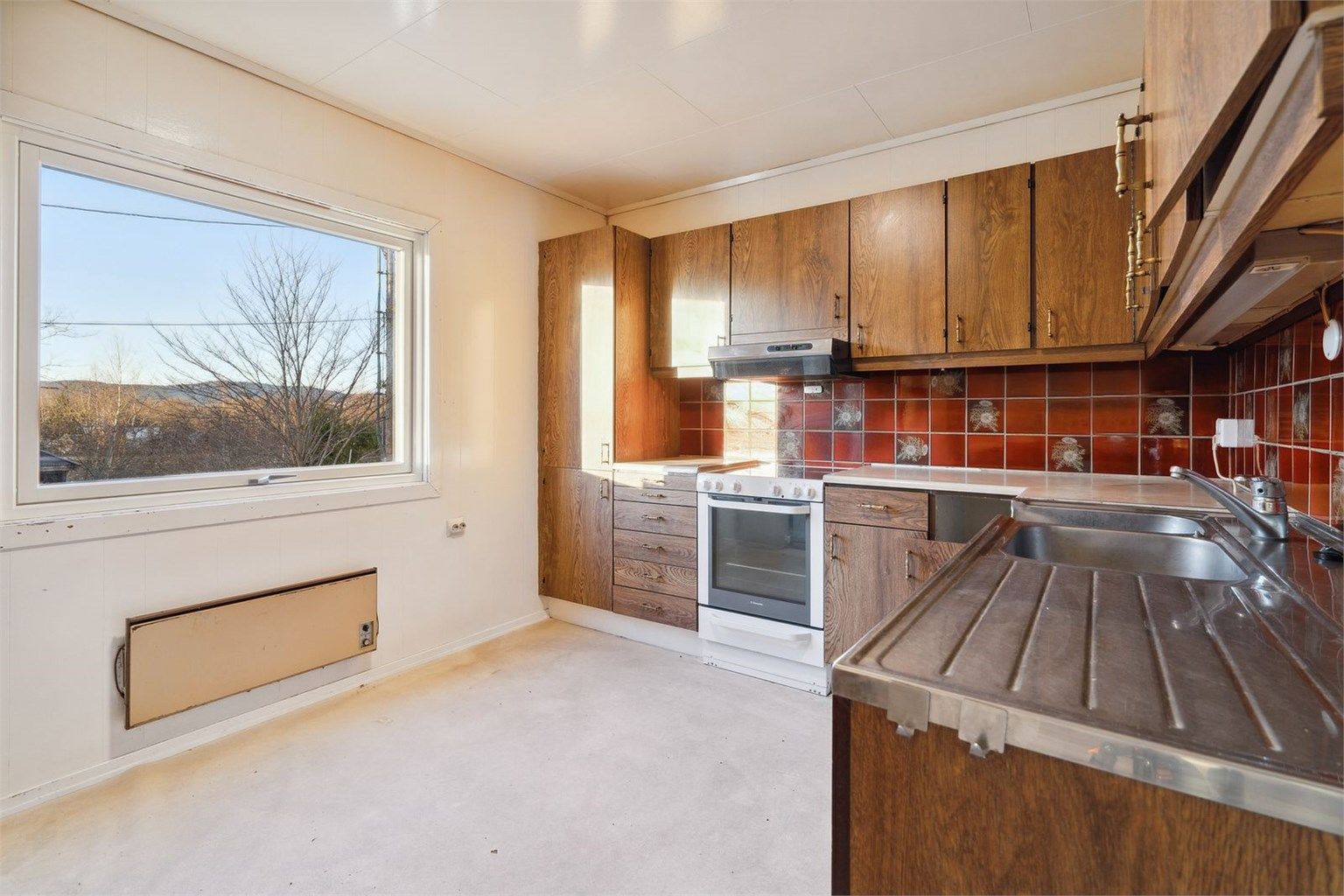 Kjøkken med stor vindusflate og svært godt med skap- og benkeplass.