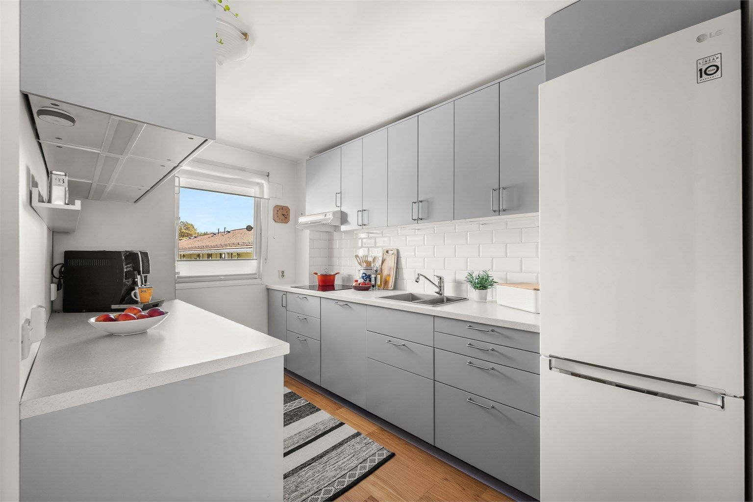 Innredningen har slette fronter og laminatbenkeplater langs to vegger, noe som gir gode arbeidsflater. Under overskapene er det benkebelysning og stikkontakter. 