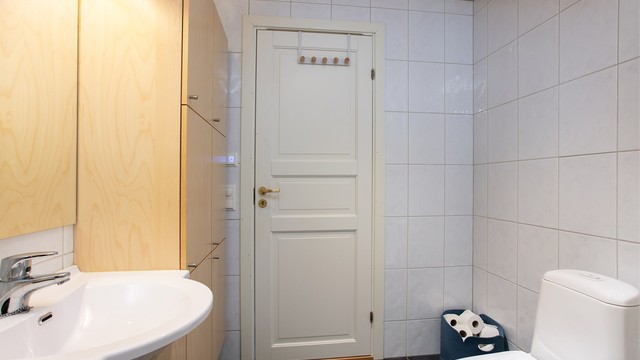 Helhetsinntrykk av badet med flislagte overflater og profilert innerdør.