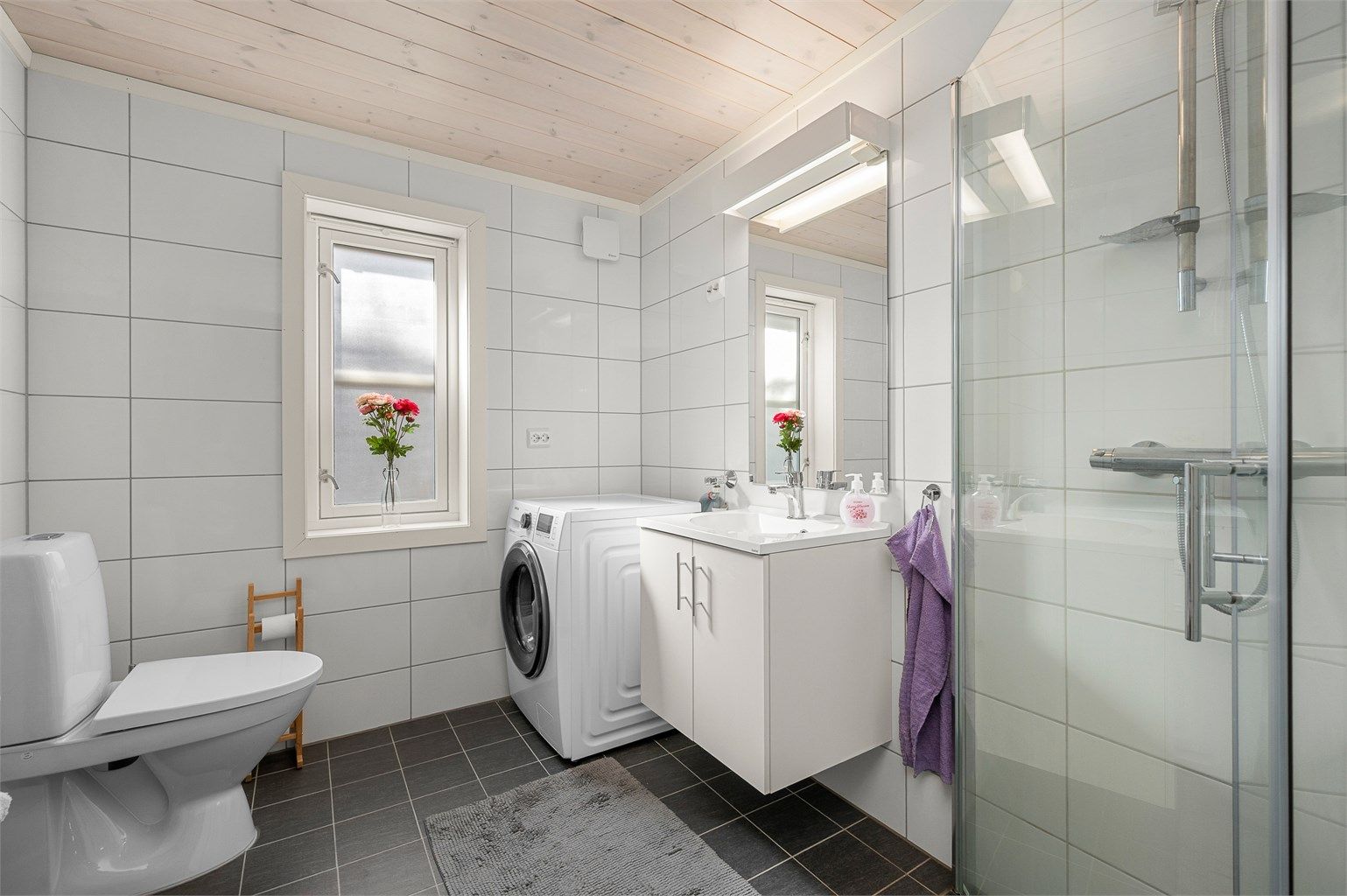 Delikat flislagt bad fra byggeår 2018 med varmekabler i gulv, moderne innredning og opplegg for vaskemaskin. Praktisk planløsning med dusjhjørne, servant og gode lysforhold.