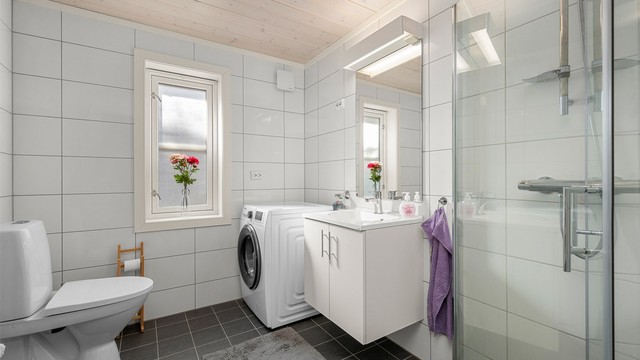 Delikat flislagt bad fra byggeår 2018 med varmekabler i gulv, moderne innredning og opplegg for vaskemaskin. Praktisk planløsning med dusjhjørne, servant og gode lysforhold.