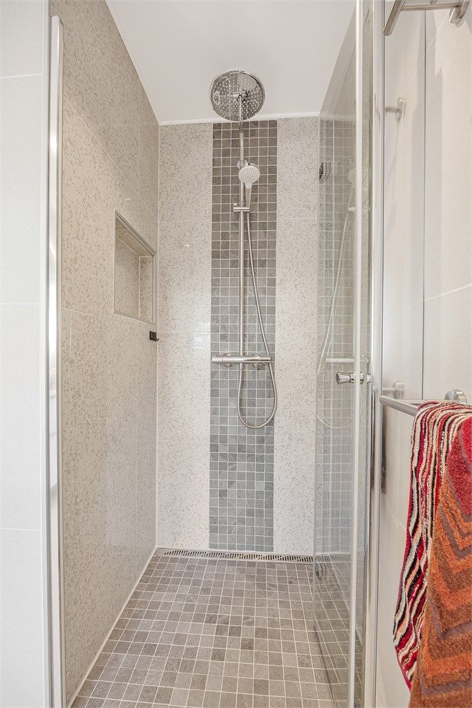 Dusjhjørne med innfellbare glassdører, mosaikkfliser og regndusj.