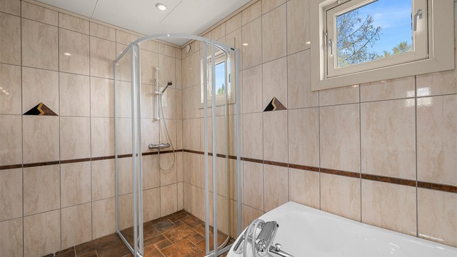 Badet måler 7 kvm og er innredet med servantskap med speil og lys, badekar og dusjhjørne.