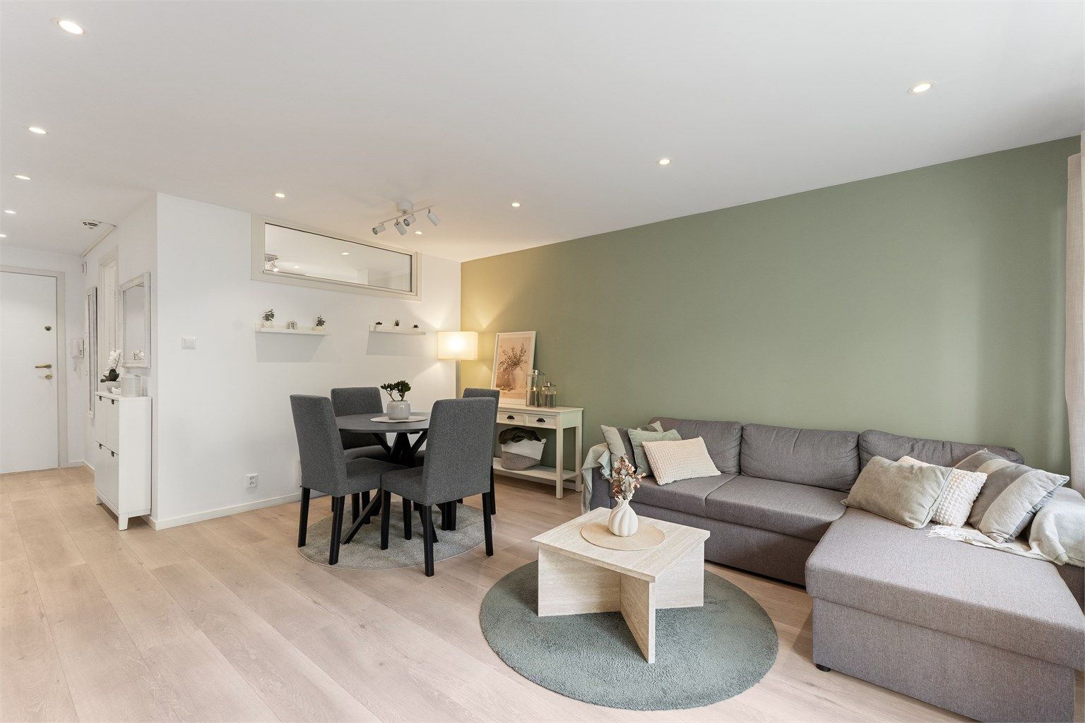 Stuen har god plass til både sofagruppe og spisebord, med gjennomgående laminatgulv og malte veggflater.