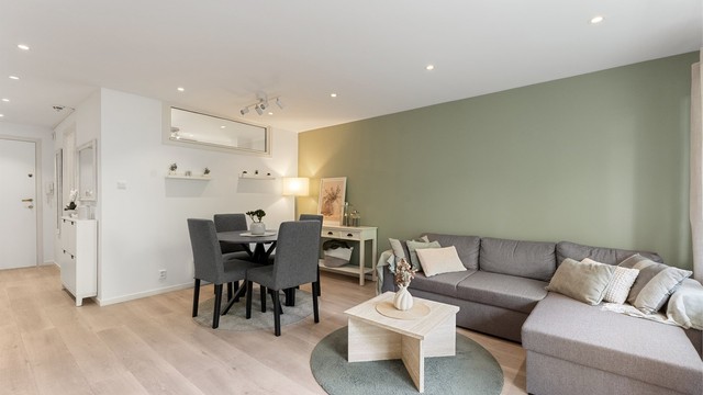 Stuen har god plass til både sofagruppe og spisebord, med gjennomgående laminatgulv og malte veggflater.