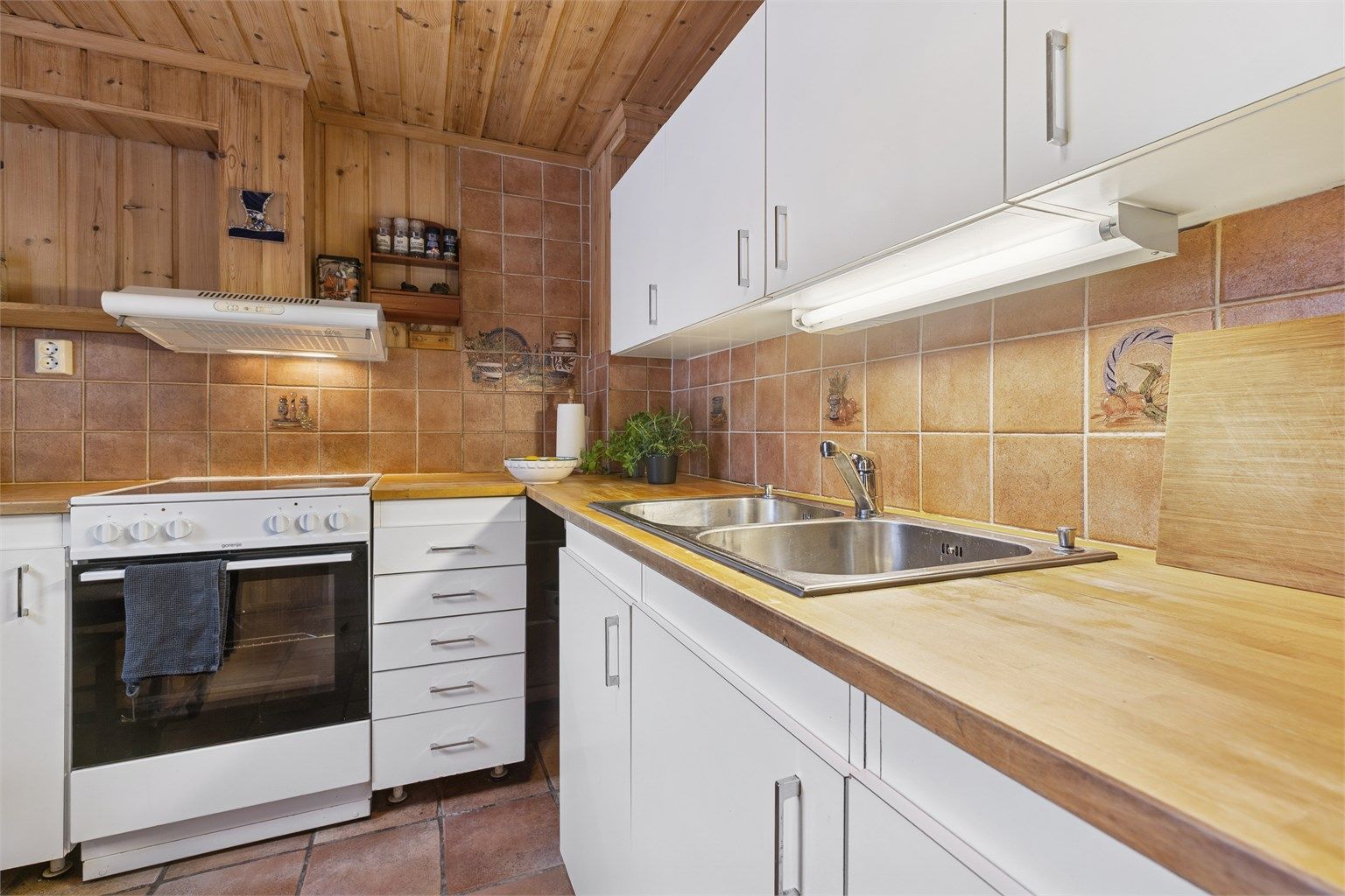 Det er flislagte vegger over kjøkkenbenkene, og god belysning under overskapene.