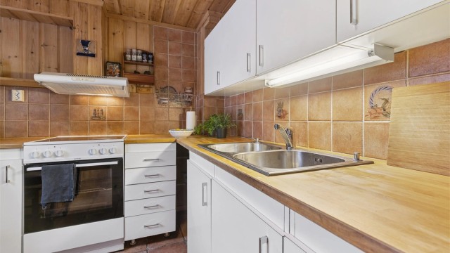 Det er flislagte vegger over kjøkkenbenkene, og god belysning under overskapene.