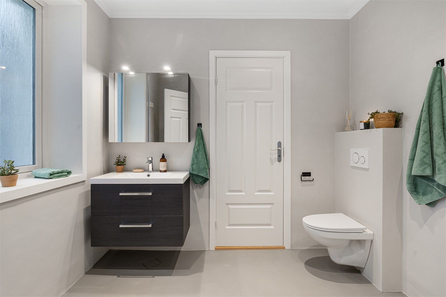 Fra kjøkkenet er det videre tilkomst til badet, som nylig er oppusset. Det er benyttet mikrosement på vegg- og gulvflater