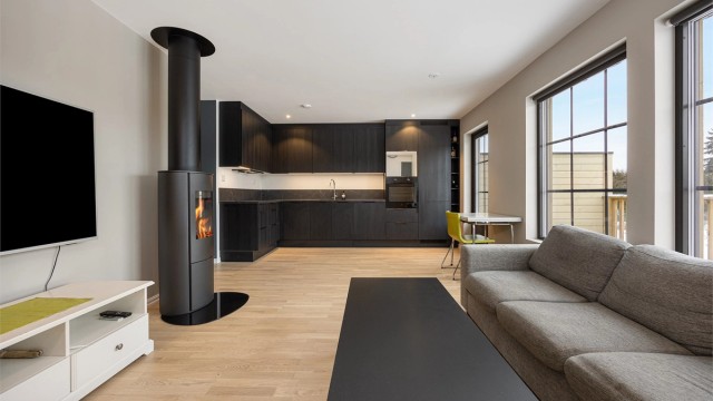 Stue og kjøkken utgjør et åpent og sosialt allrom med gjennomgående parkett på gulvet.
