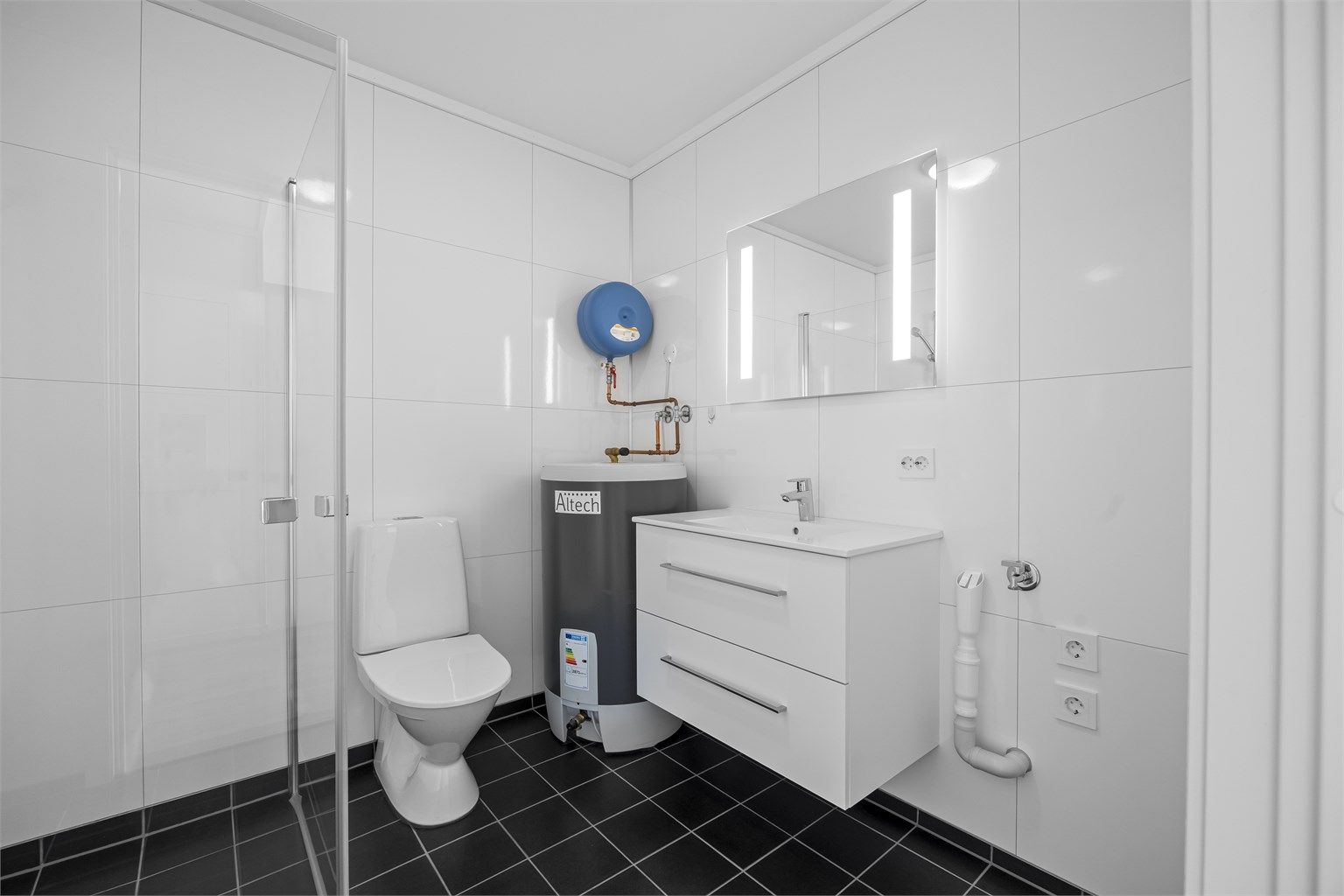 Badet har vannbåren gulvvarme, innredning med servant, dusjhjørne og opplegg for vaskemaskin.