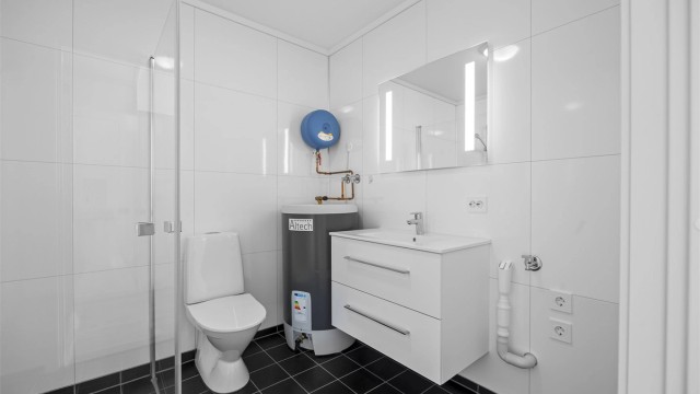 Badet har vannbåren gulvvarme, innredning med servant, dusjhjørne og opplegg for vaskemaskin.
