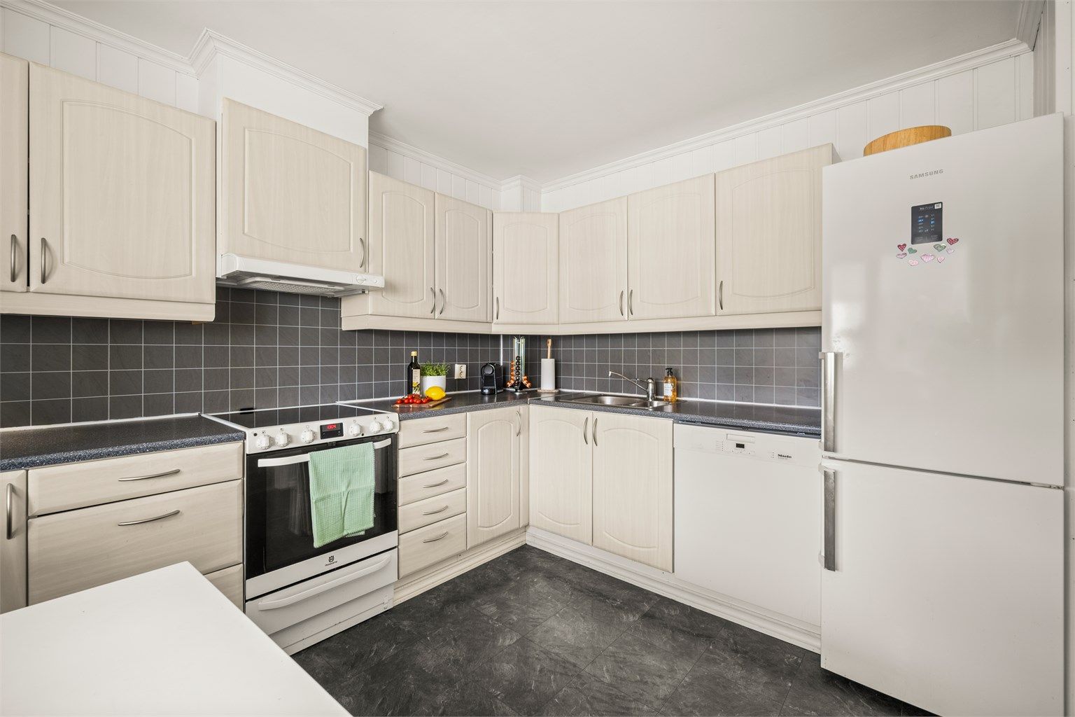 Kjøkkeninnredning med profilerte fronter og laminatbenkeplate. Komfyr og kombiskap medfølger handelen.