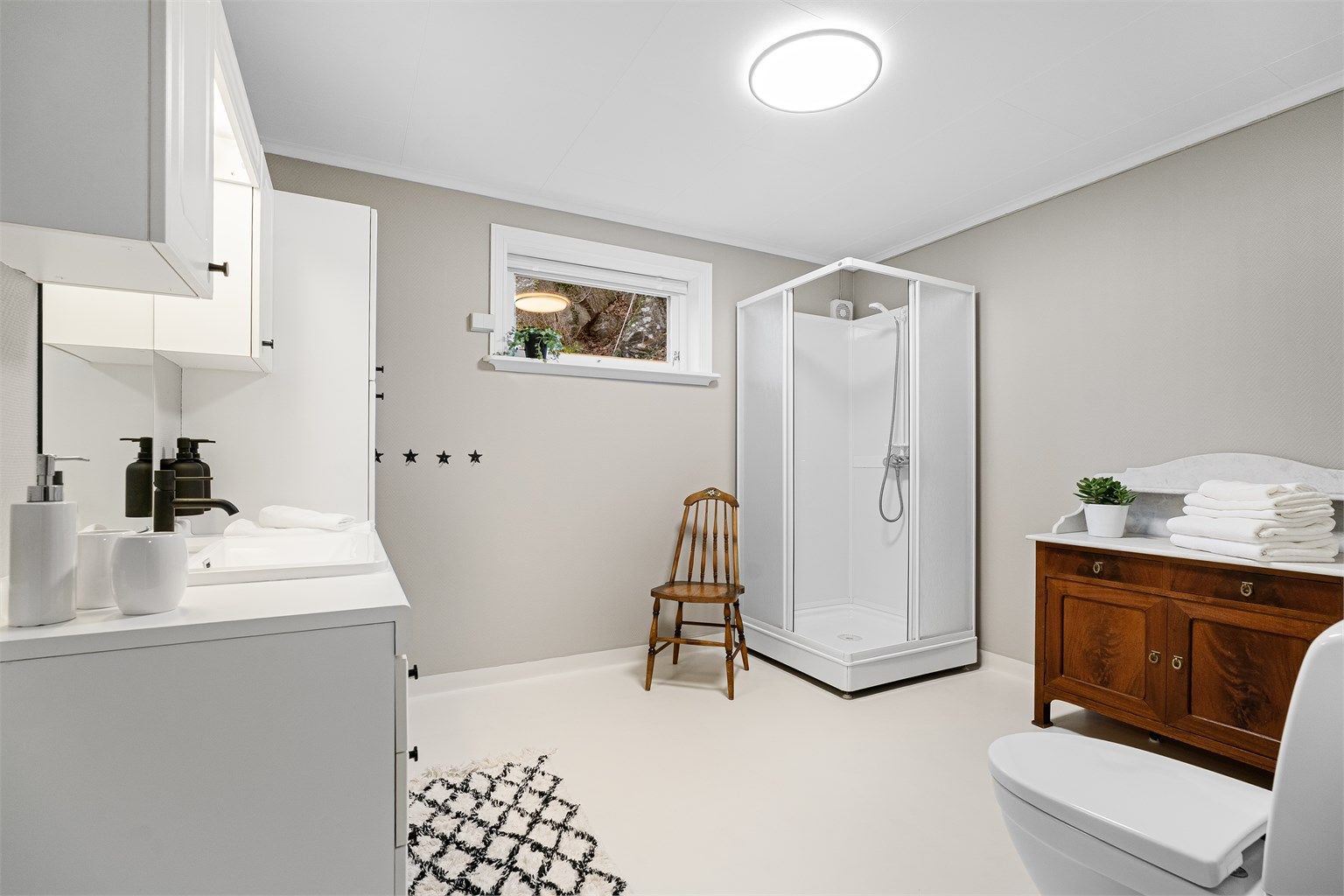 Bad nr. 2 har dusjkabinett, toalett, nyere servant og blandebatteri samt godt med oppbevaringsplass. Det er også opplegg til badekar til høyre i bildet. 