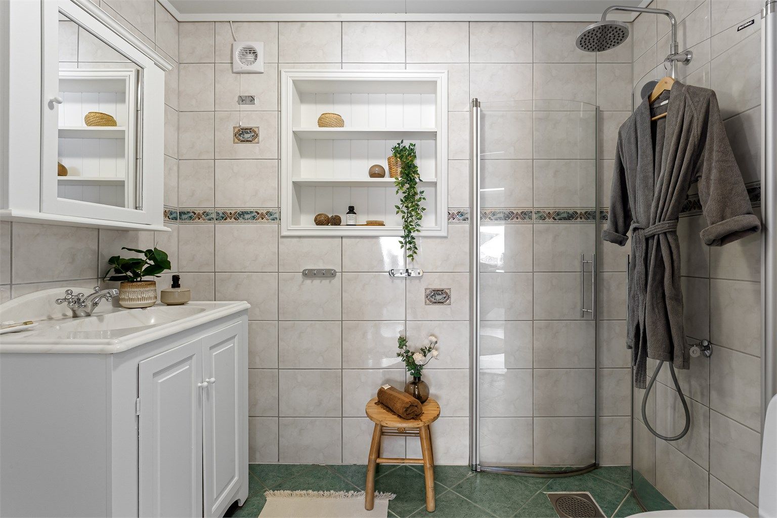 Flislagt bad med gulvvarme. Innredning med profilerte malte fronter og heldekkende servant.