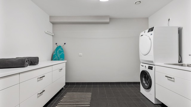 Vaskerom med flislagt gulv med varme og vegger i malte flater. Baderomsinnredning med slette fronter. Benkeplate av laminat. Nedfelt oppvaskkum av rustfritt stål med ett-greps. Mekanisk avtrekksventil på vegg. Opplegg for vaskemaskin/tørketrommel.