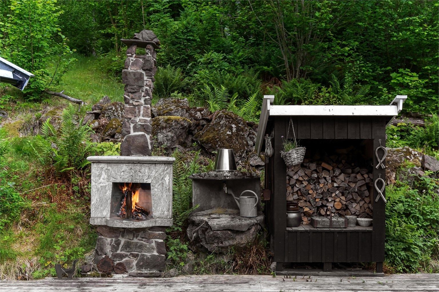 Utepeisen er bygget i naturstein og ledsages av et praktisk, overbygget vedskjul.