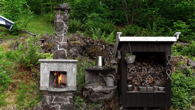 Utepeisen er bygget i naturstein og ledsages av et praktisk, overbygget vedskjul.