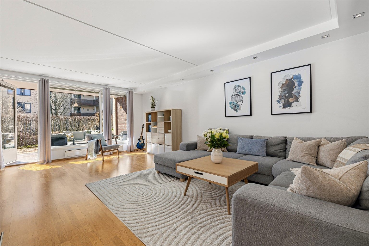 Lys og romslig stue med parkett på gulv og down-lights i tak. 