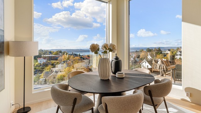 Store vindusflater fra gulv til tak slipper inn rikelig med dagslys og skaper en sømløs forbindelse mellom ute og inne