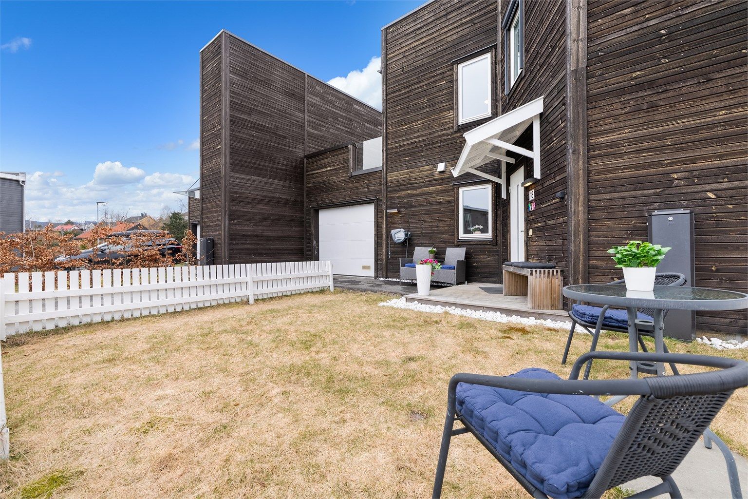 Hyggelig inngjerdet plenareale ved inngangsparti hvor morgenkaffen kan nytes på koselige sommerdager