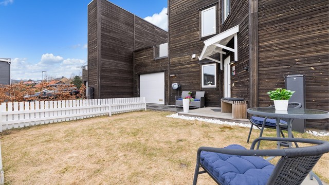 Hyggelig inngjerdet plenareale ved inngangsparti hvor morgenkaffen kan nytes på koselige sommerdager