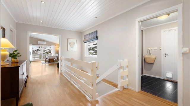 Gangen leder videre inn mot stuen og kjøkkenet, og har trapp ned til underetasjen.