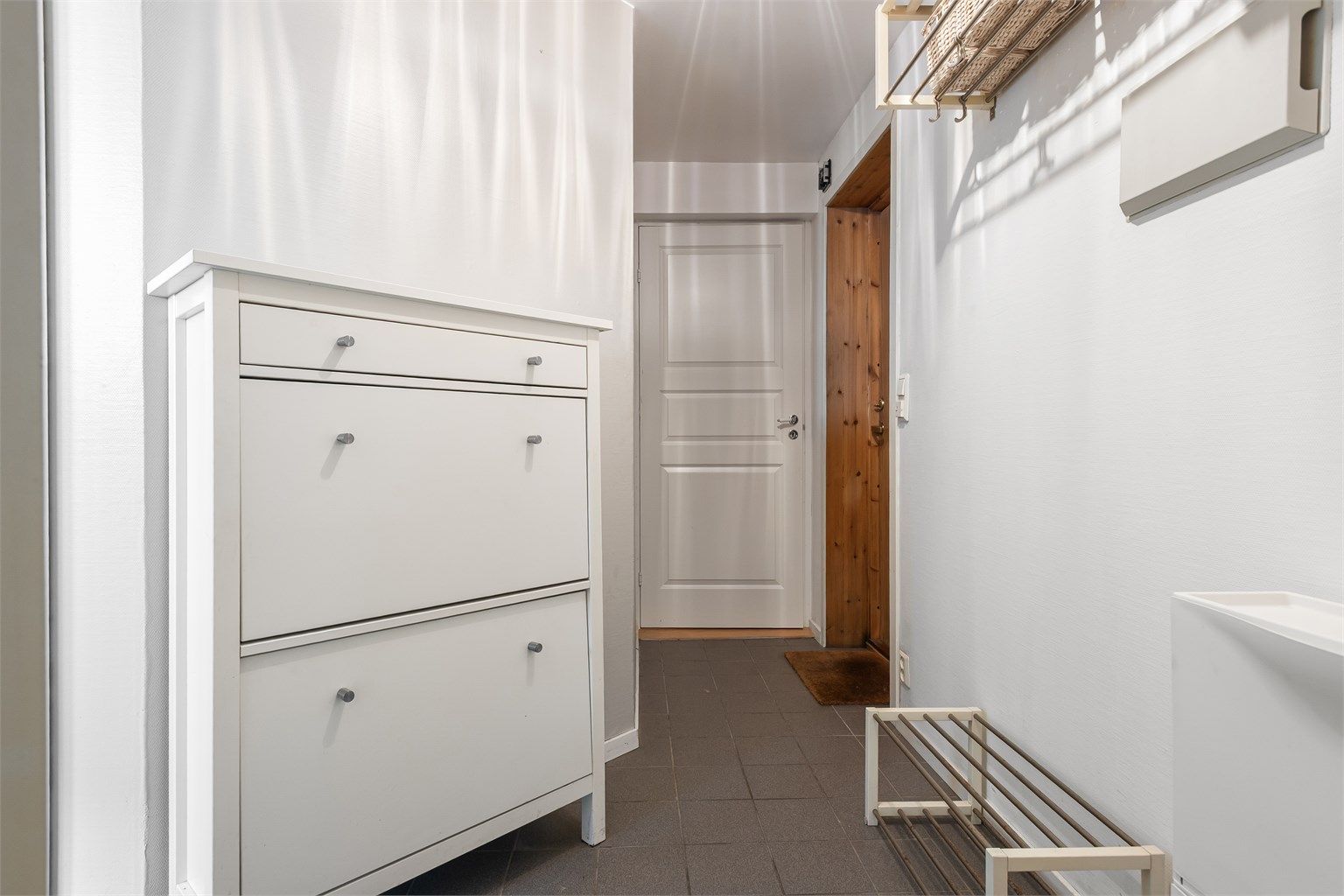 Entré/gang med gulvfliser med gulvvarme og plass til oppheng for yttertøy. Adkomst til entréen via utvendig kjellertrapp