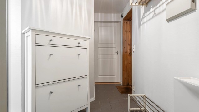 Entré/gang med gulvfliser med gulvvarme og plass til oppheng for yttertøy. Adkomst til entréen via utvendig kjellertrapp