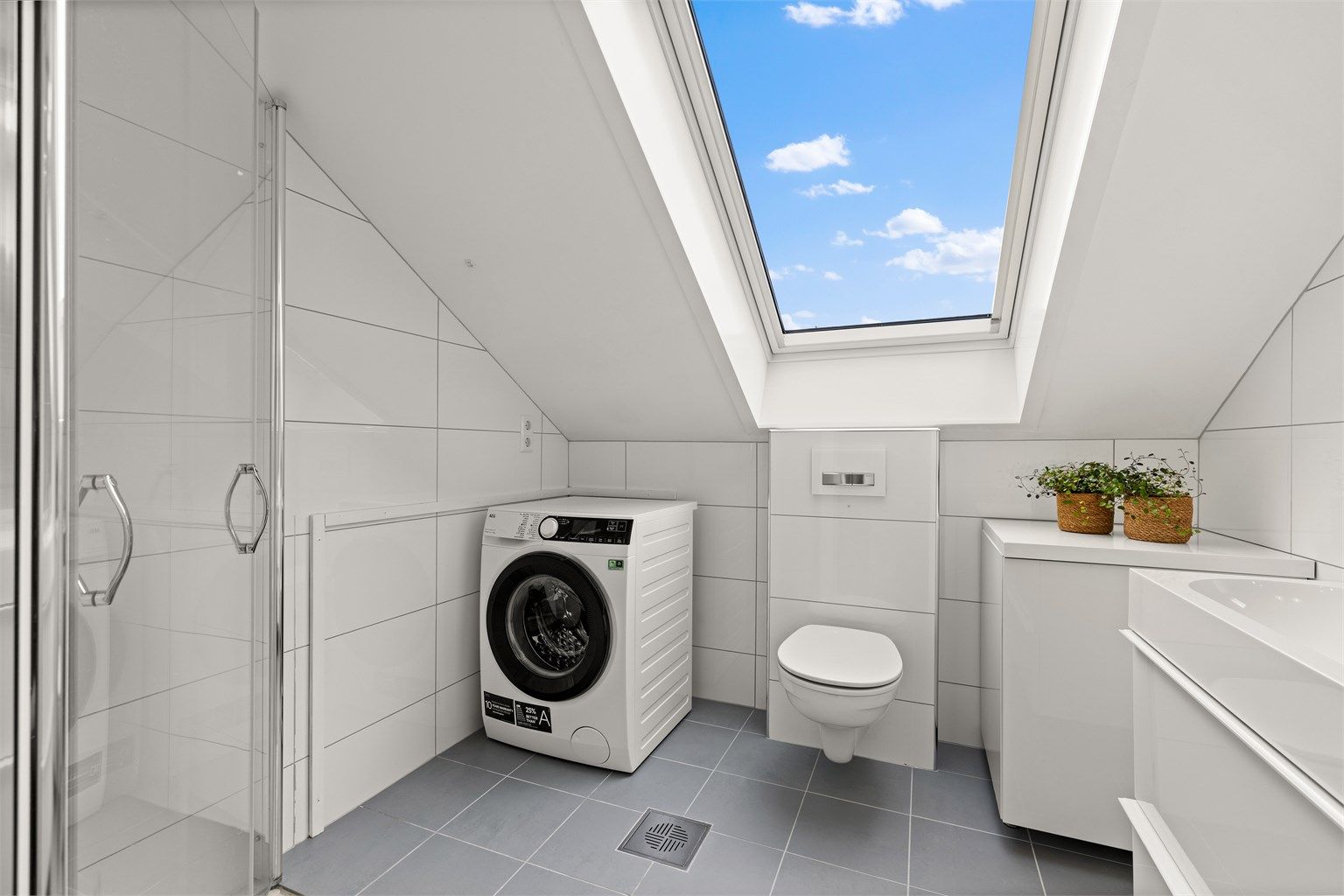 Badet har en heldekkende servant med doble armaturer og innfellbare dusjdører i glass.