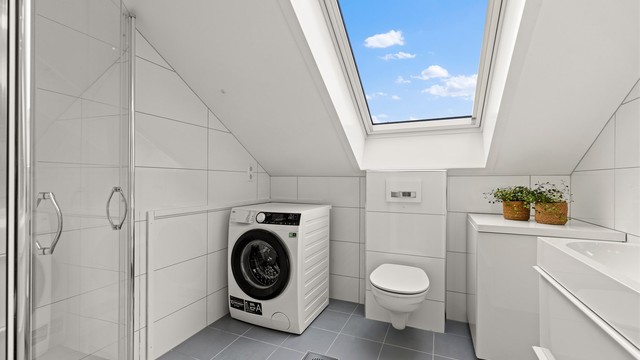 Badet har en heldekkende servant med doble armaturer og innfellbare dusjdører i glass.