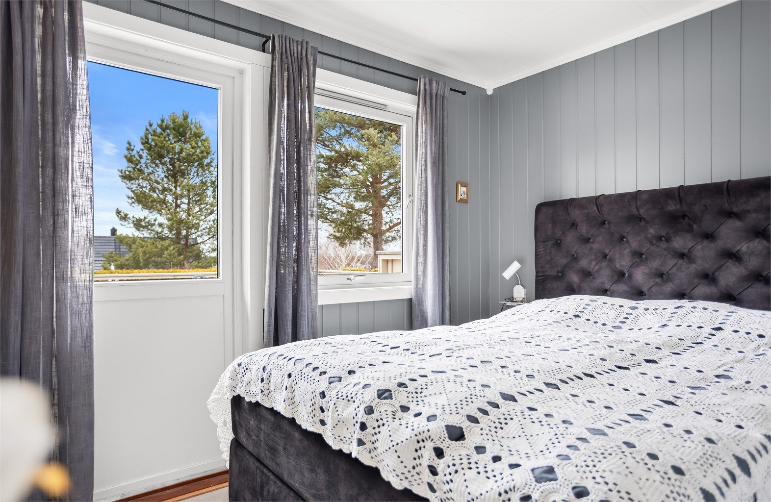 Soverom med god plass til dobbeltseng, garderobeløsning og naturlig lys fra vindu og terrassedør.