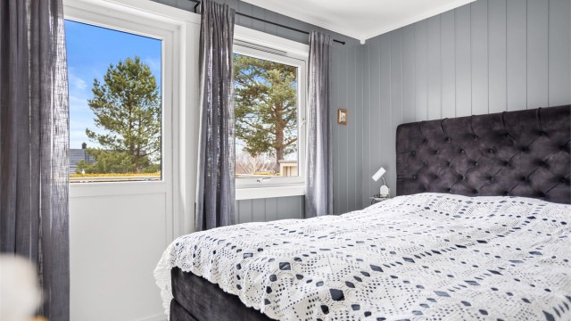 Soverom med god plass til dobbeltseng, garderobeløsning og naturlig lys fra vindu og terrassedør.
