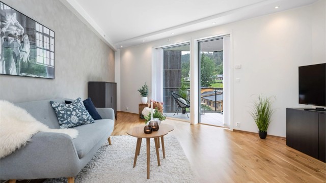 Stuen har spotter i tak og store vindusflater som gir godt med lysinslipp. Kalkmalingen på veggen skaper en behagelig atmosfære.