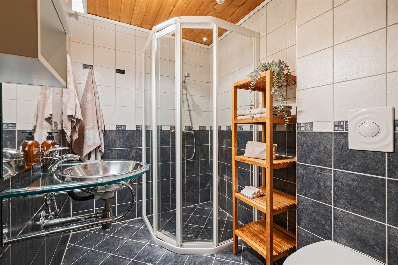 Pent flislagt bad med servant med overskap og speil med lys, dusjhjørne og toalett. Rommet er ikke godkjent for varig opphold.