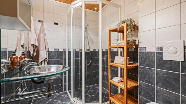 Pent flislagt bad med servant med overskap og speil med lys, dusjhjørne og toalett. Rommet er ikke godkjent for varig opphold.