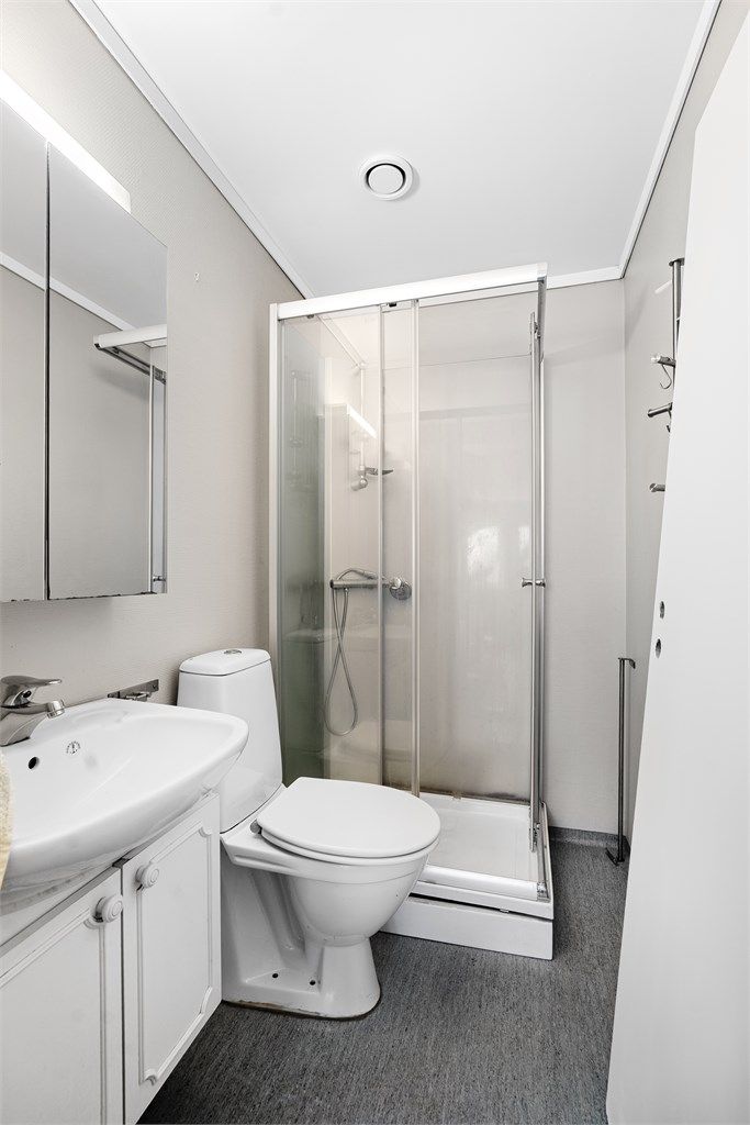 Badet er utstyrt med dusjkabinett, servant og toalett